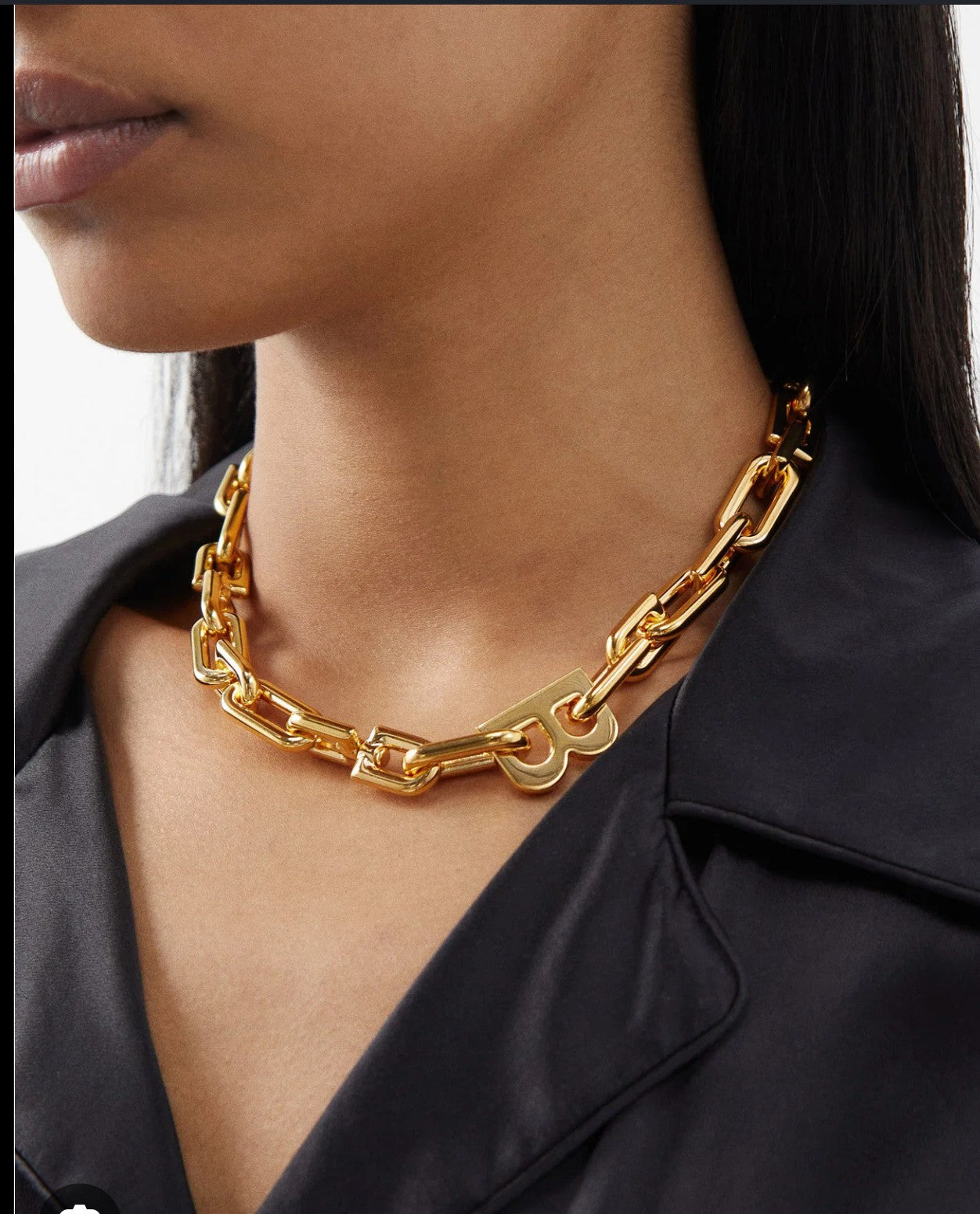 Noticed Atelier by Legzdiamond Balenciaga gold chain choker with iconic B logo worn on a model in a black top.