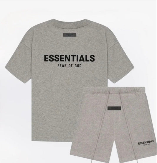 A heather gray two-piece outfit set from Fear of God Essentials, featuring a short-sleeve t-shirt with 'ESSENTIALS FEAR OF GOD' printed in black on the chest, and matching drawstring shorts with a small black logo on the lower leg.