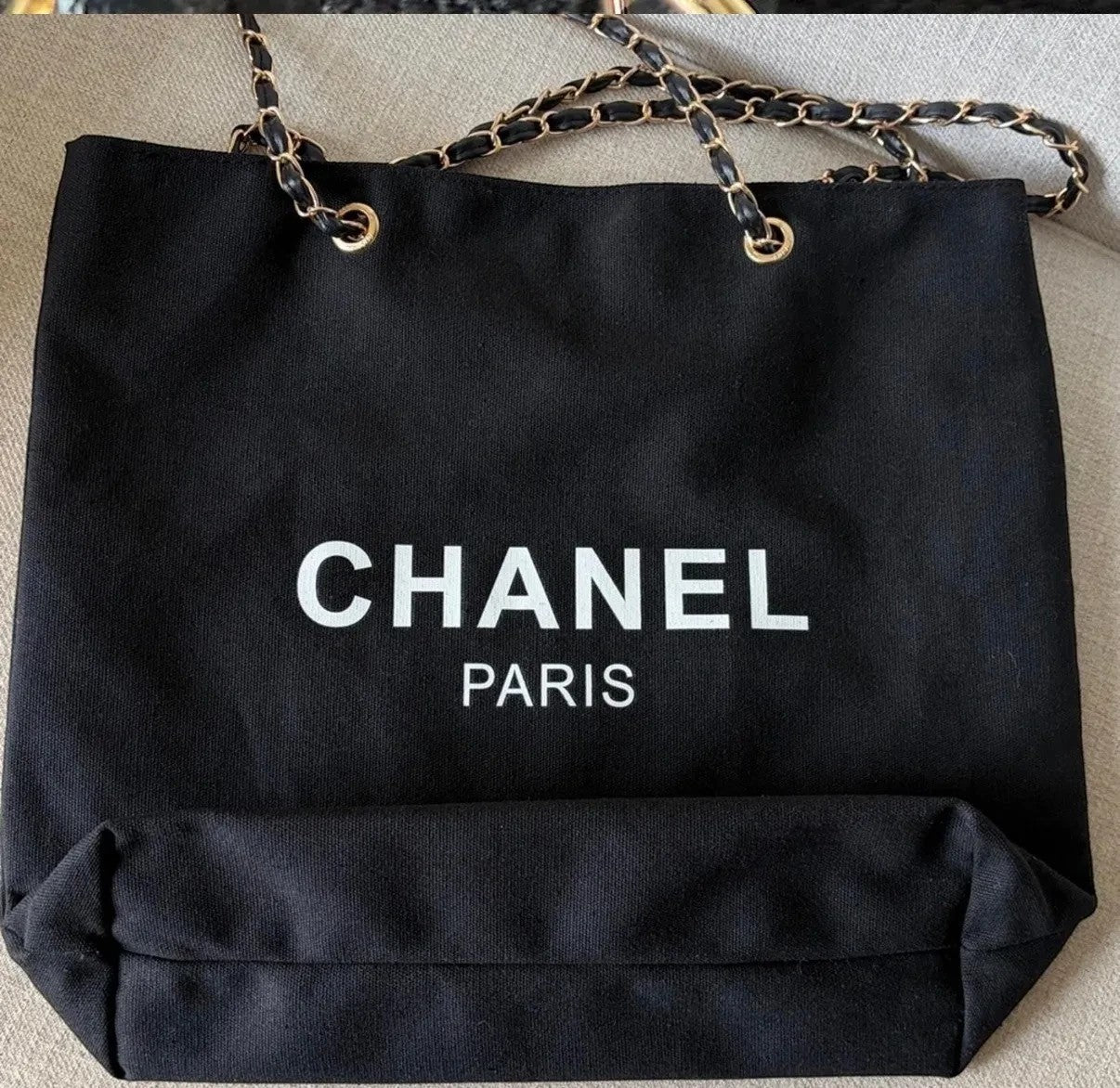 Noticed Atelier by Legzdiamond black canvas Chanel Paris tote with gold chain straps and white logo lettering