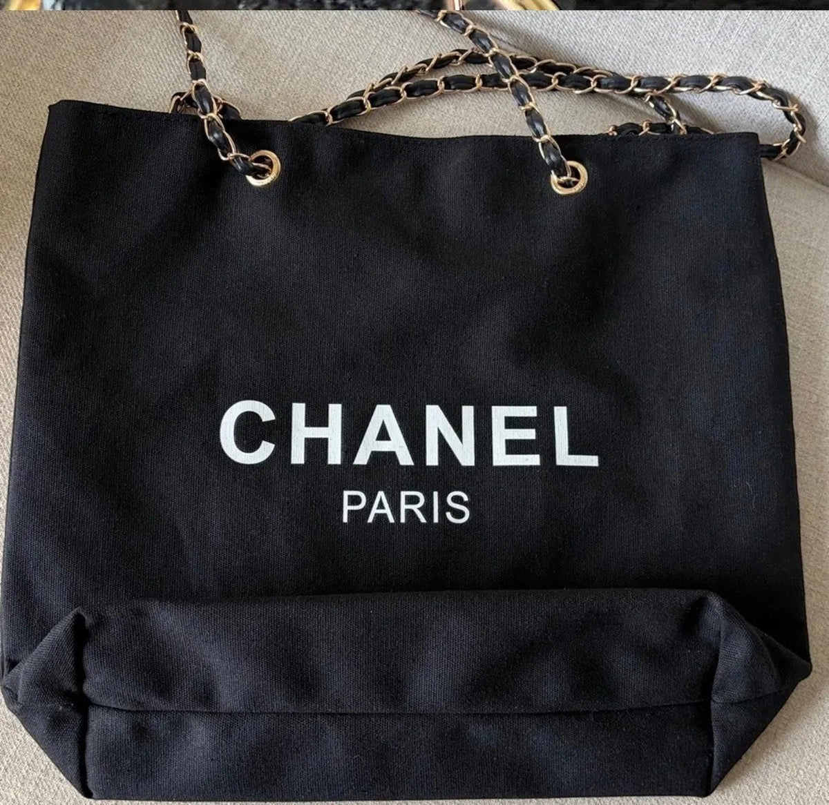 Noticed Atelier by Legzdiamond black canvas Chanel Paris tote with gold chain straps and white logo lettering