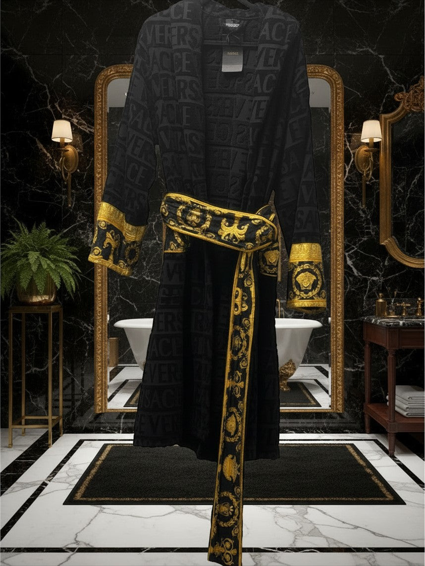 Noticed Atelier by Legzdiamond black plush cotton bathrobe with gold Baroque print cuffs and embossed logo pattern.