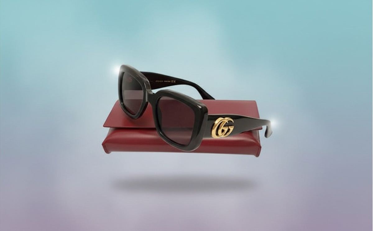 Noticed Atelier by Legzdiamond Gucci black sunglasses with gold GG logo hardware resting on a red case